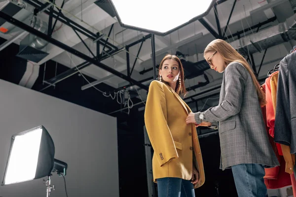 Estilista en gafas de pie con hermosa modelo en estudio de fotos - foto de stock