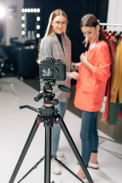 Selective focus of digital camera with happy stylist standing with trendy model on screen — Stock Photo