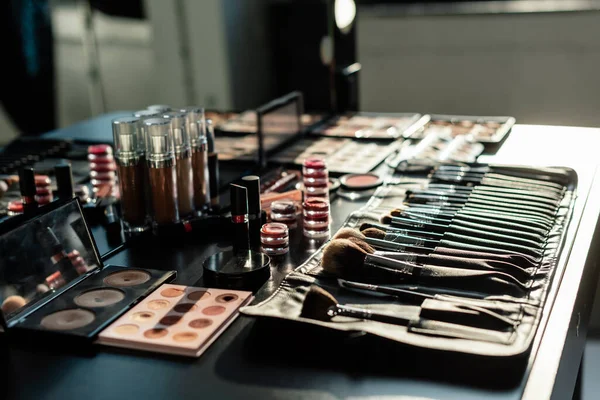 Foco seletivo do conjunto de pincel de maquiagem perto de cosméticos decorativos — Fotografia de Stock