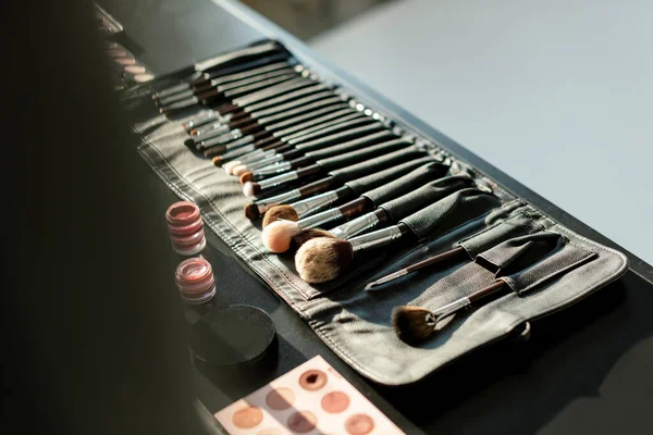 Enfoque selectivo de cepillo de maquillaje conjunto cerca de bálsamos labiales y sombras de ojos — Stock Photo