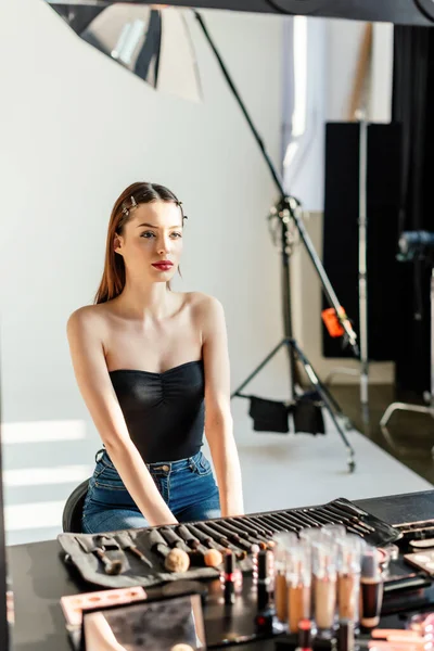 Selective focus of beautiful model looking at mirror in photo studio — Stock Photo