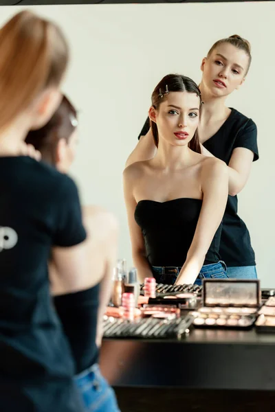 Selective focus of make up artist near model and decorative cosmetics — Stock Photo