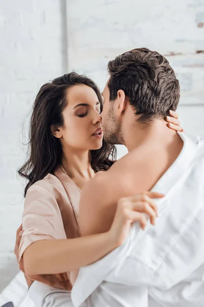Selective focus of couple hugging and woman undressing businessman in bedroom — Stock Photo