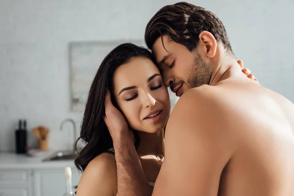 Passionate couple with closed eyes hugging in kitchen — Stock Photo