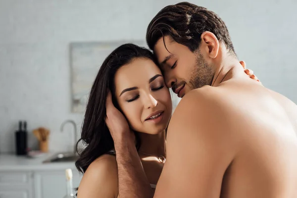 Pareja apasionada con los ojos cerrados abrazándose en la cocina - foto de stock