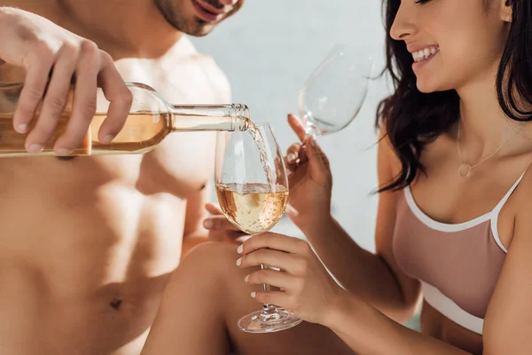 Обрізаний вид чоловіка, що поливає вино і дівчину, посміхається і тримає окуляри — стокове фото