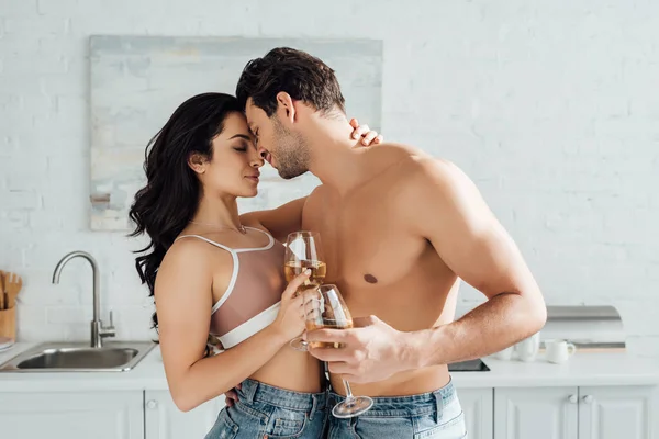 Pareja con copas de vino abrazándose en la cocina — Stock Photo