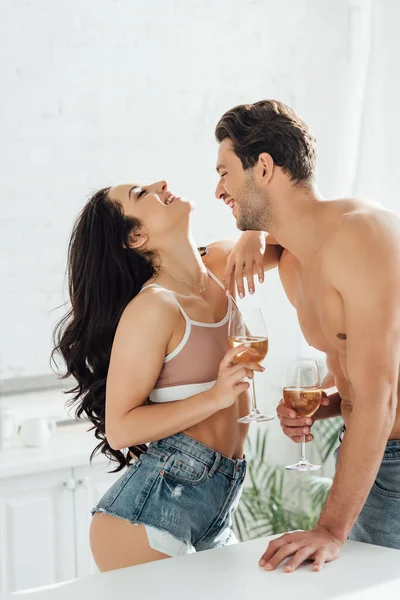 Couple with glasses of wine smiling near table in kitchen — Stock Photo