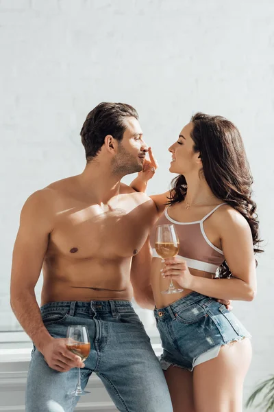 Couple with glasses of wine smiling, looking at each other and girl touching male nose — Stock Photo