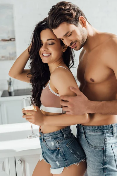 Novio abrazando sexy chica con copa de vino por detrás - foto de stock
