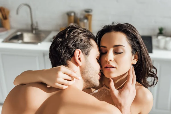 Leidenschaftliche Frau und Mann mit geschlossenen Augen umarmen sich in der Küche — Stockfoto