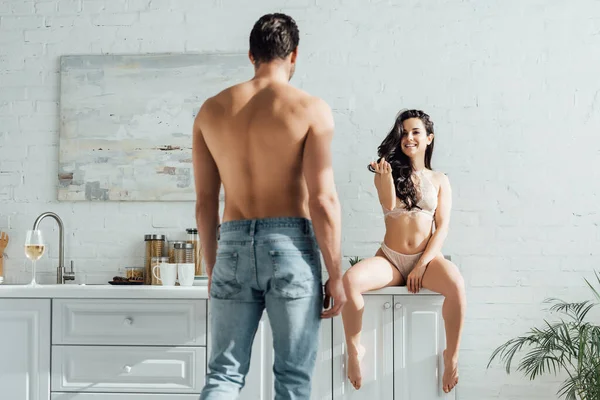 Mann vor heißem Mädchen auf Küchenschrank sitzend und lächelnd — Stockfoto