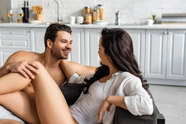 Casal olhando um para o outro e sorrindo no sofá na cozinha — Fotografia de Stock