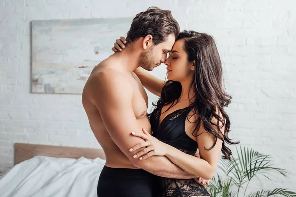 Bonito homem abraçando com mulher sexy no quarto — Fotografia de Stock