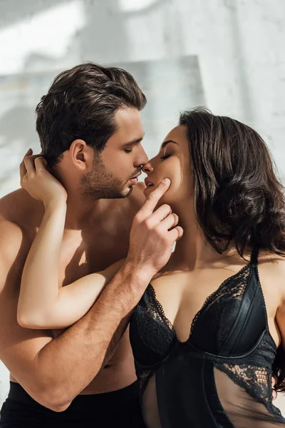 Apasionada novia besándose con novio con los ojos cerrados en el dormitorio - foto de stock