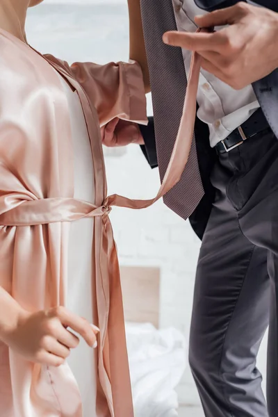 Cropped view of woman and businessman holding female girdle — Stock Photo