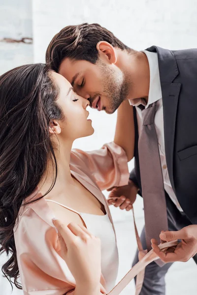 Businessman kissing girl with closed eyes and holding female girdle — Stock Photo