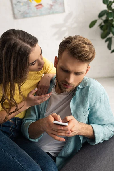 Woman talking to boyfriend with smartphone on couch — Stock Photo