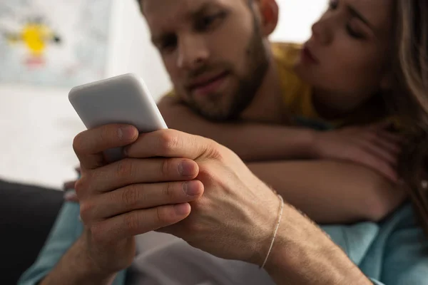 Foco seletivo do homem usando smartphone perto de bela namorada — Fotografia de Stock