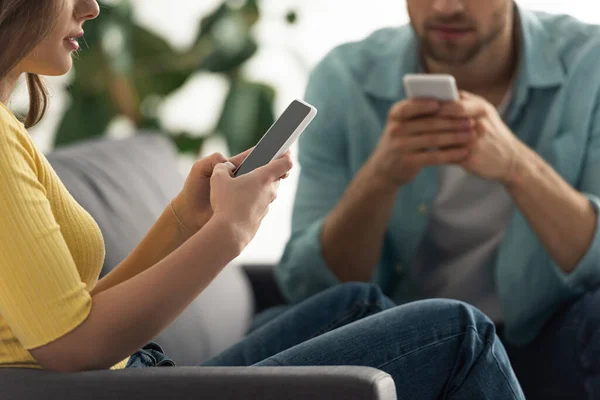 Vista cortada do casal viciado usando smartphones no sofá — Fotografia de Stock