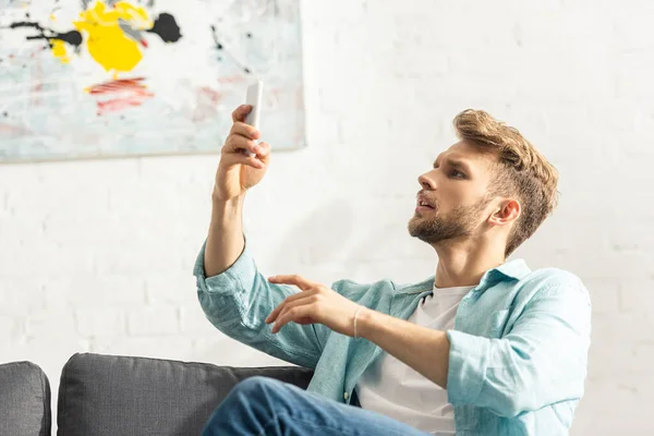 Hombre guapo usando teléfono inteligente en la sala de estar - foto de stock