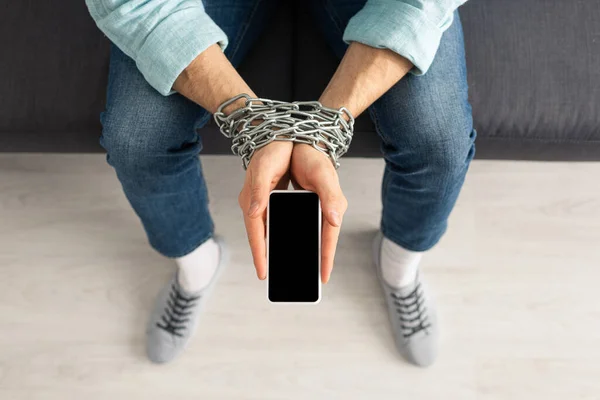Vista superior del hombre con cadena alrededor de las manos sosteniendo el teléfono inteligente con pantalla en blanco — Stock Photo