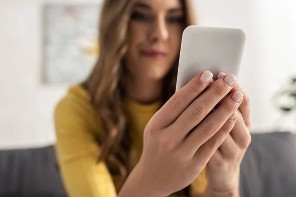 Selective focus of woman holding smartphone on sofa — Stock Photo