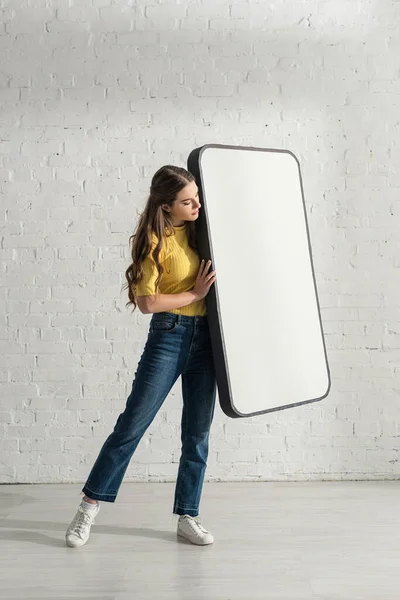 Atractiva mujer sosteniendo el modelo de teléfono inteligente en casa - foto de stock