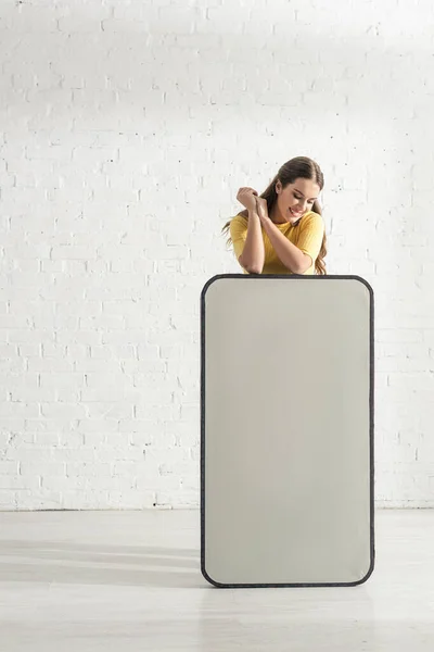 Красивая женщина улыбается, стоя рядом с большой моделью смартфона — стоковое фото
