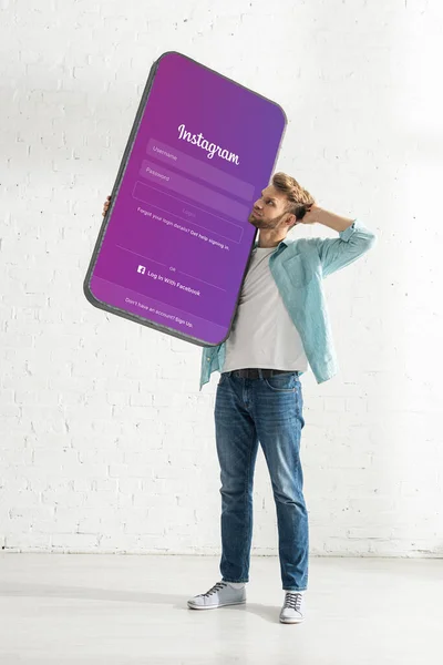 KYIV, UCRÂNIA - Fevereiro 21, 2020: Homem pensativo segurando modelo de smartphone com aplicativo instagram — Fotografia de Stock