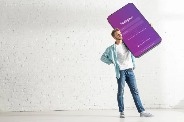 KYIV, UCRANIA - 21 de febrero de 2020: Hombre guapo sosteniendo el modelo de teléfono inteligente con aplicación instagram - foto de stock