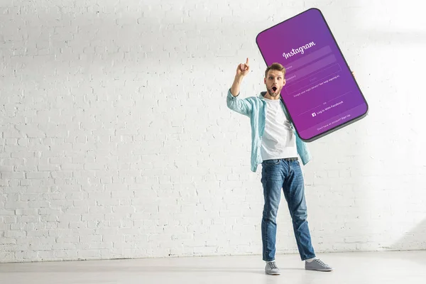 KYIV, UKRAINE - FEBRUARY 21, 2020: Excited man showing solution gesture while holding model of smartphone with instagram app — Stock Photo