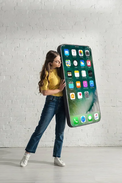 KYIV, UKRAINE - FEBRUARY 21, 2020: Attractive girl holding model of smartphone with iphone screen at home — Stock Photo