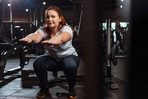 Selective focus of concentrated overweight squatting with outstretched hands — Stock Photo