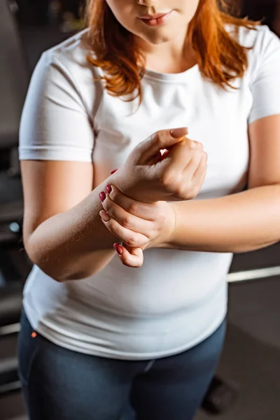 Recortado vista de la chica con sobrepeso comprobar el pulso con la mano - foto de stock