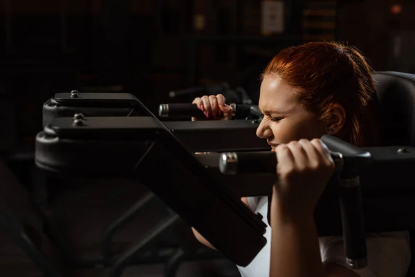 Целеустремленная девушка с избыточным весом делает упражнения по удлинению рук на тренажере — стоковое фото