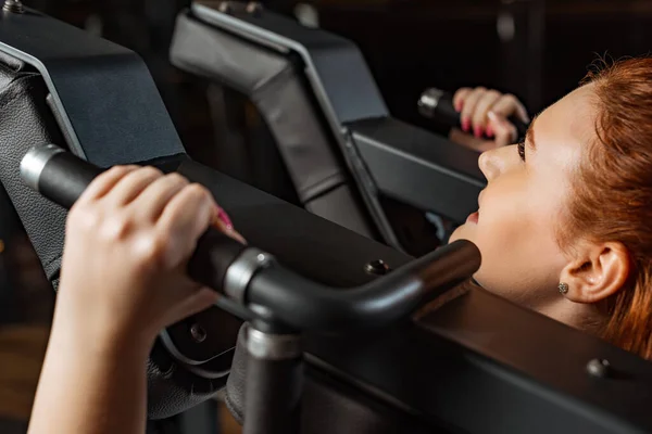 Cropped view of overweight girl doing arms extension exercise on fitness machine — Stock Photo