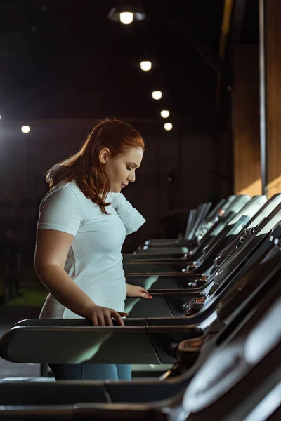 Концентрированный избыточный вес девушки тренировки на беговой дорожке в тренажерном зале — стоковое фото