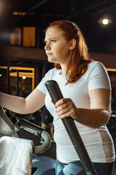 Confident overweight girl training on stepper in sports center — Stock Photo