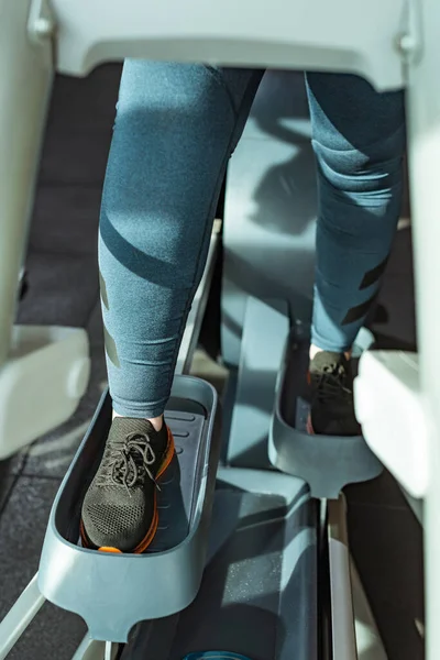 Cropped view of overweight girl training on step machine in gym — Stock Photo