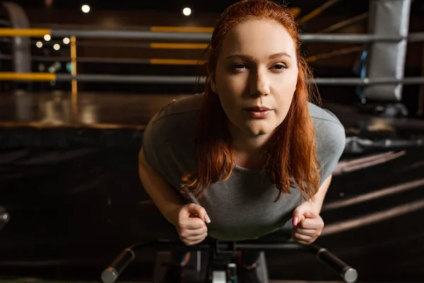 Focused overweight girl doing lower back extension exercise on training machine — Stock Photo