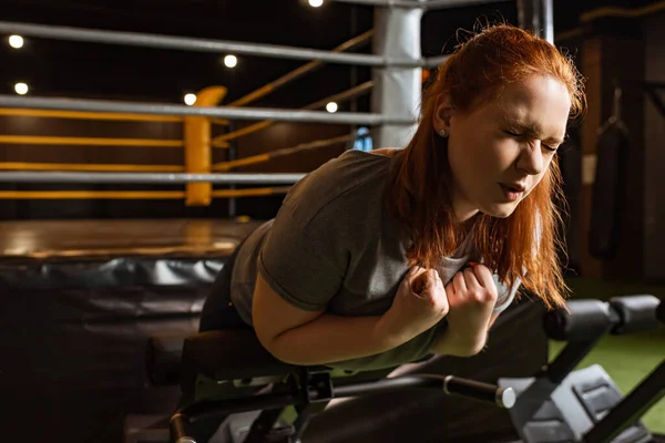 Fille en surpoids avec les yeux fermés faisant un exercice d'extension du bas du dos sur la machine d'entraînement — Photo de stock