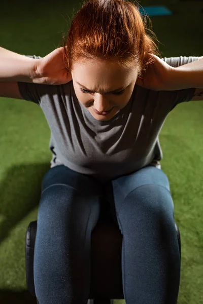 Vista aerea della ragazza intenzionale in sovrappeso che fa esercizio addominale sulla macchina fitness — Foto stock