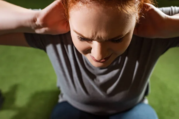 Blick über den Kopf eines absichtlich übergewichtigen Mädchens, das Bauchmuskeltraining auf einem Fitnessgerät macht — Stockfoto