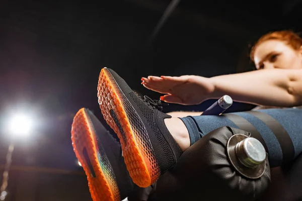 Low angle view of overweight girl doing abs exercise on fitness machine — Stock Photo