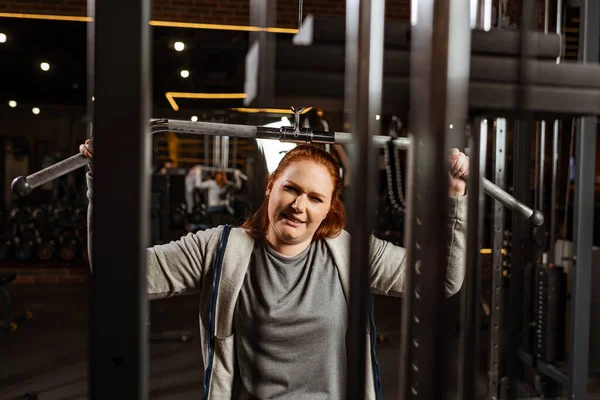 Selective focus of overweight girl doing arms extension exercise on training machine — Stock Photo