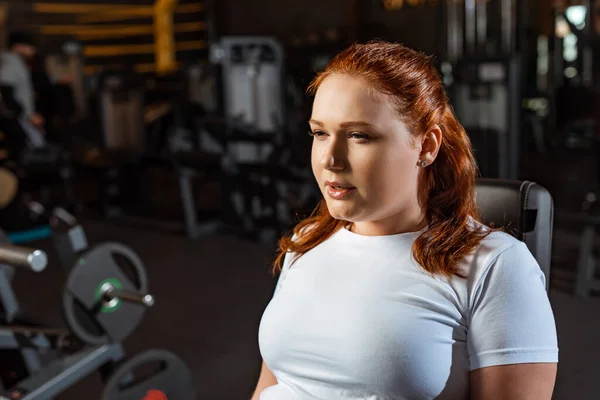 Confident, pretty overweight girl in white t-shirt training in gym — Stock Photo