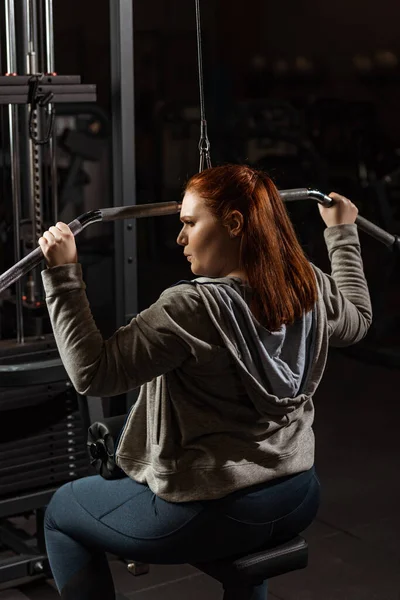 Fiduciosa ragazza in sovrappeso che fa esercizio di estensione delle braccia sulla macchina fitness — Foto stock