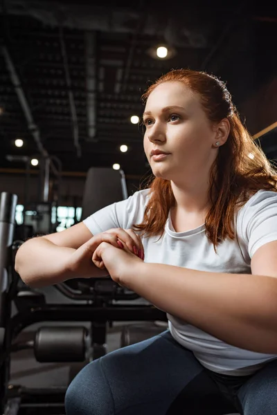 Confident overweight girl squatting with clenched hands in gym — Stock Photo