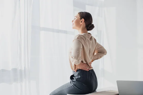 Tired businesswoman stretching back in modern office — Stock Photo